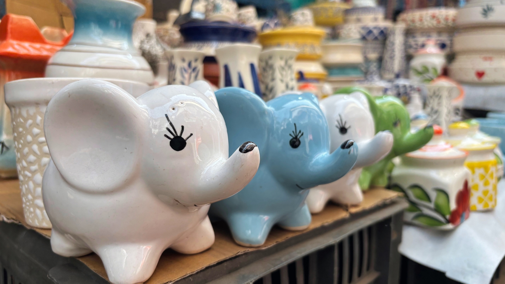 <p>Ceramic elephant containers stand shoulder to shoulder.</p>